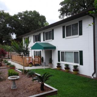 A two-story white house with a well-maintained garden and lawn.