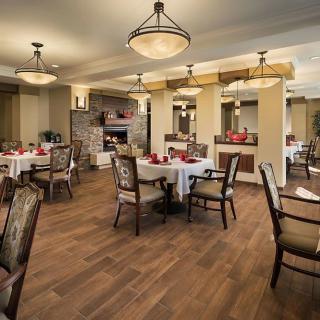 A well-decorated dining room with neatly arranged tables and chairs, featuring elegant lighting fixtures.