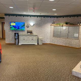 A spacious lobby area with a television, water cooler, and seating options.