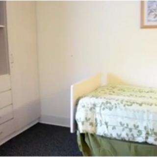 A minimalist bedroom with a single bed and built-in wardrobe.