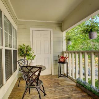 A cozy balcony with a small table and two chairs, surrounded by plants and overlooking greenery.