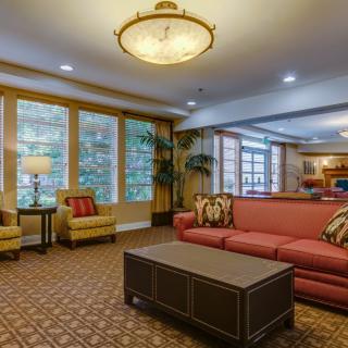 A cozy living room with a red sofa, armchairs, and large windows providing natural light.