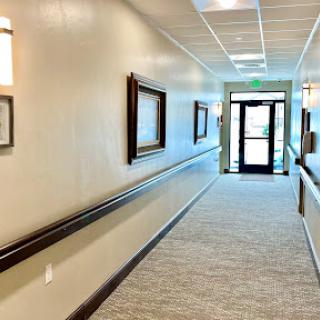 A well-lit hallway featuring framed artworks and a doorway leading outside.
