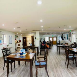 A spacious restaurant interior with neatly arranged tables and chairs on a wooden floor.