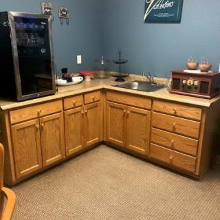 A kitchenette area with wooden cabinets, a sink, and appliances including a coffee maker and beverage cooler.