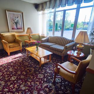 A cozy living room with a sofa, armchairs, a coffee table, and large windows letting in natural light.