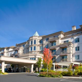 A hotel building with a landscaped entrance and clear blue sky.