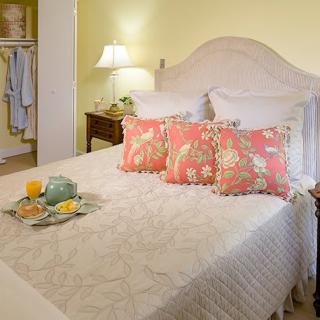 A cozy bedroom with a neatly made bed adorned with decorative pillows and a bedside lamp.