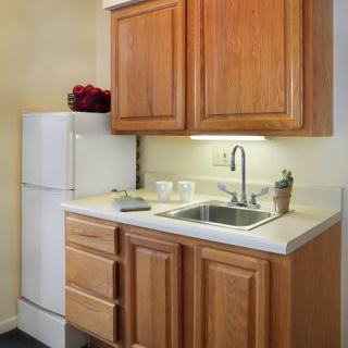 A compact kitchen area featuring wooden cabinets, a sink, and a refrigerator.