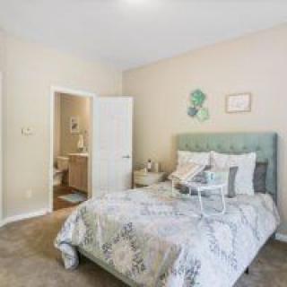 A cozy bedroom with a neatly made bed and a view into an adjoining bathroom.