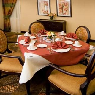 An elegantly set dining table with neatly arranged chairs, showcasing fine tableware and napkin decor in a restaurant setting.