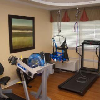 A rehabilitation room with exercise equipment, including a stationary bike and treadmill.