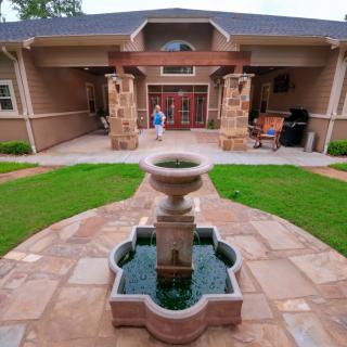 A landscaped front yard with a central fountain leading up to a house entrance.