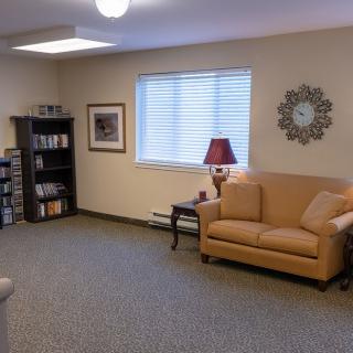 A cozy living room with a sofa, bookshelf, and lamp.