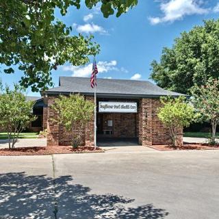 A small brick post office with an American flag, surrounded by trees under a blue sky.
