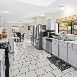 A spacious, modern kitchen with stainless steel appliances and white cabinetry, leading to a dining area.
