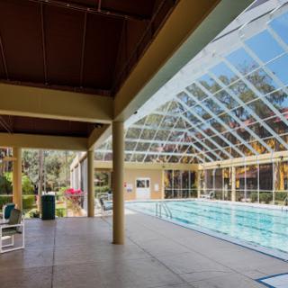 A spacious indoor swimming pool with a glass roof, providing a bright and inviting atmosphere for relaxation and leisure activities.