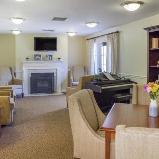 A cozy living room featuring a fireplace, television, piano, and comfortable seating.