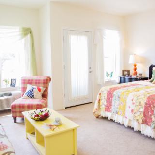 A bright and cozy bedroom with colorful decor and a comfortable seating area.
