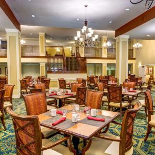 An elegant dining area with neatly arranged tables and chairs, adorned with chandeliers.