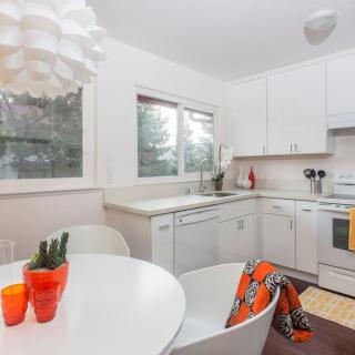 A modern kitchen with white cabinets, a dining table, and minimalist decor.