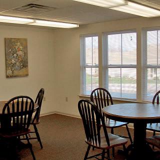 A dining area with multiple tables and chairs, well-lit by natural light from large windows.
