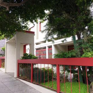 A modern house with a red fence and lush greenery.