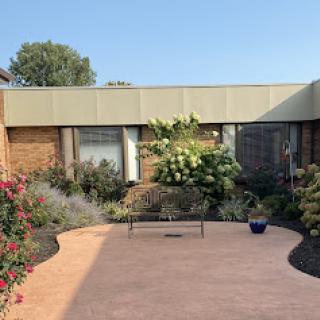 A peaceful courtyard garden featuring a bench surrounded by flowering plants.