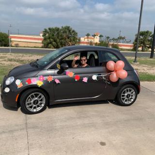 A cheerful, decorated car ready for a celebration with balloons and flowers.