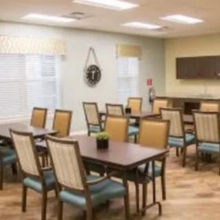 A neatly arranged dining room with tables and chairs, featuring bright lighting and a homely interior design.