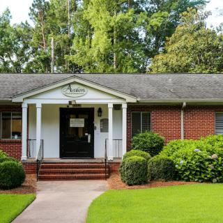 A charming brick building surrounded by well-maintained landscaping and lush greenery.