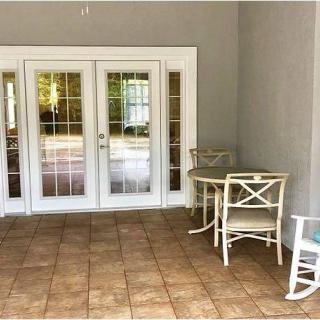 A cozy patio area with a table and two chairs, featuring tiled flooring and glass doors leading inside.