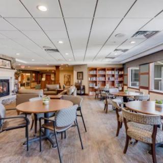 A cozy lounge area with round tables, comfortable seating, a fireplace, and bookshelves.