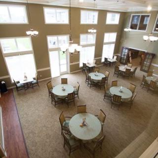 An aerial view of a dining room with round tables and chairs, large windows, and ample lighting.
