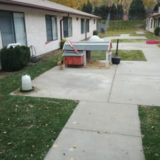 A view of a residential area with green lawns, concrete paths, and parked objects.