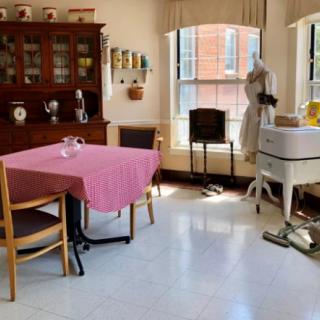 A vintage kitchen interior with a wooden cabinet, table, chairs, and retro appliances.