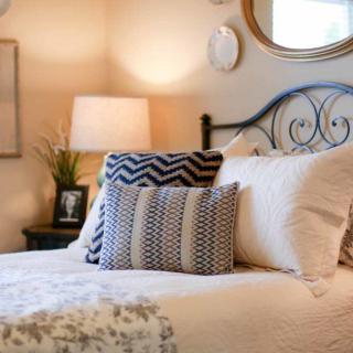A cozy bedroom interior with decorative pillows and a lamp beside a bed.