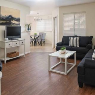 A cozy living room with dark sofas, a white coffee table, and a television on a stand.