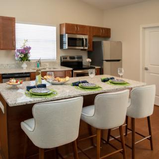 A modern kitchen featuring wood cabinetry and stainless steel appliances, complete with an island for dining and preparation.