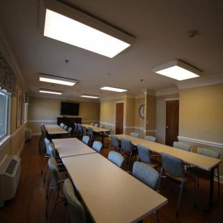 A well-lit conference room with tables and chairs arranged for a meeting.