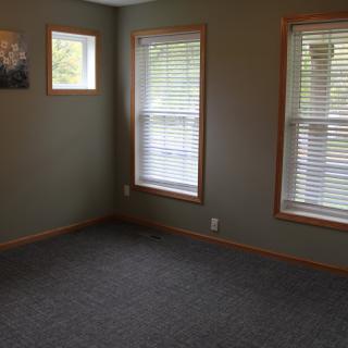 An empty room with carpet and windows featuring blinds.