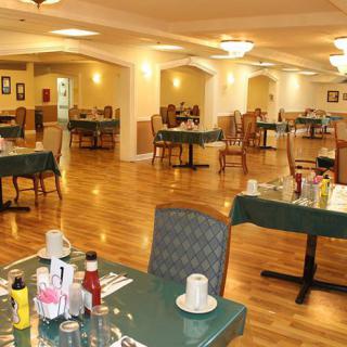 An empty dining area with wooden floors and neatly arranged tables and chairs.