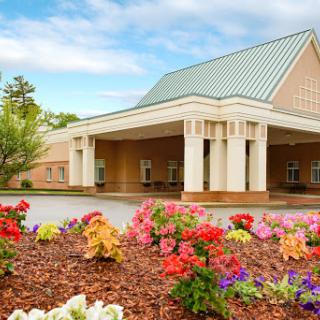 A welcoming entrance to a beautifully landscaped building surrounded by vibrant flowers.