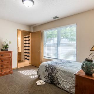 A cozy bedroom with a bed, dresser, and window providing natural light.