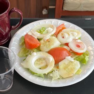 A fresh salad with tomatoes, onions, and lettuce served on a white plate.
