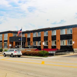A modern hotel building featuring brick architecture and a parking area.