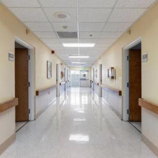 A clean and well-lit hospital corridor with multiple doors.