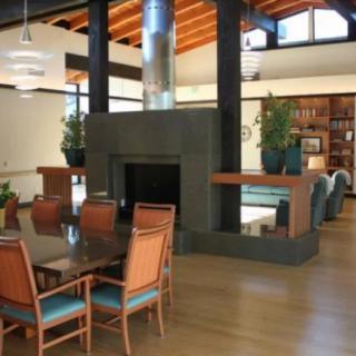 A modern open-plan interior featuring a dining area with a fireplace and wooden flooring.