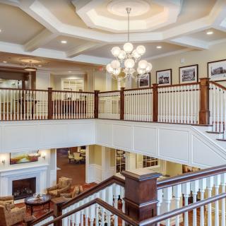 A spacious interior featuring a grand staircase with elegant railing, a chandelier, and comfortable living areas.