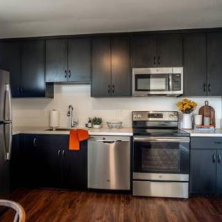 A modern kitchen with dark cabinets and stainless steel appliances.